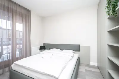 a white bedroom with a bed and a window at RentPlanet - Apartament Lubicz in Kraków