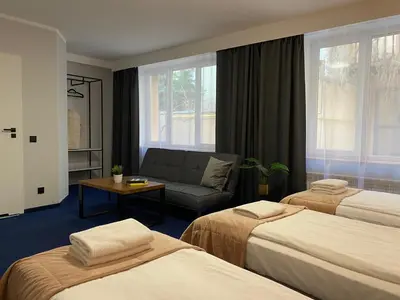 a hotel room with two beds and a couch at Cube House Aparthotel in Kraków