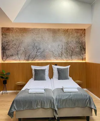 two beds in a bedroom with a painting on the wall at Cube House Aparthotel in Kraków