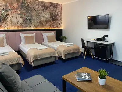 a room with two beds and a table and a tv at Cube House Aparthotel in Kraków