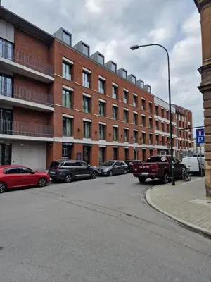 a parking lot with cars parked in front of a brick building at Apartament 338 ulica Lwowska 1 in Kraków