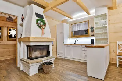 a kitchen with a fireplace in a log home at Dom na Zapotoczu. Góralski dom na wyłączność na szczycie skały. in Kasinka Mala