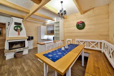 a dining room with a table and a fireplace at Dom na Zapotoczu. Góralski dom na wyłączność na szczycie skały. in Kasinka Mala