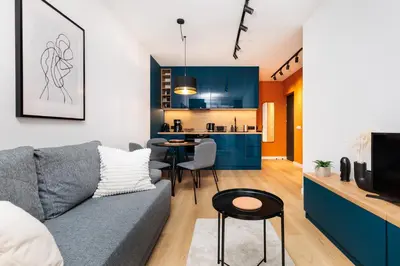 a living room with a couch and a kitchen at Colorful Cracovia Apartments - by Upstairs in Kraków