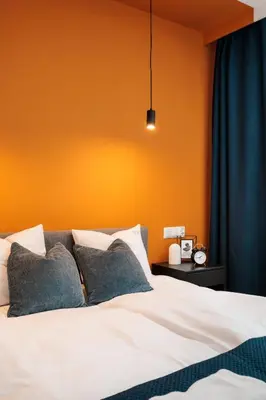a bedroom with an orange wall and a bed at Colorful Cracovia Apartments - by Upstairs in Kraków