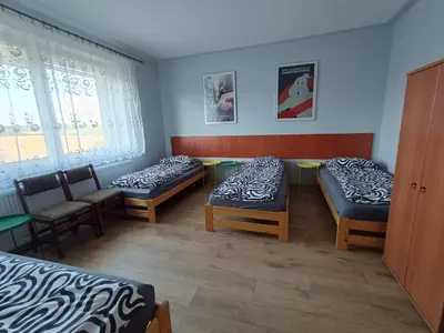 a room with three beds and chairs and windows at Noclegi nad S-ką in Miechów