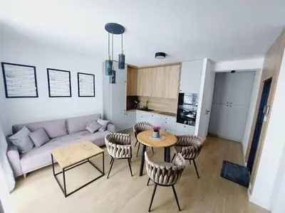 a living room with a couch and a table and chairs at Nowe mieszkanie Kraków, bezpłatny parking, AWG APARTMENTS in Kraków
