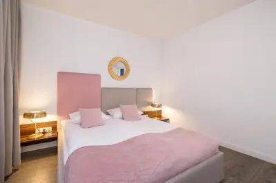 a bedroom with a large white bed with pink sheets at Blue and Green Apartment with Bright Pink Bedroom in Kraków by Noclegi Renters in Kraków