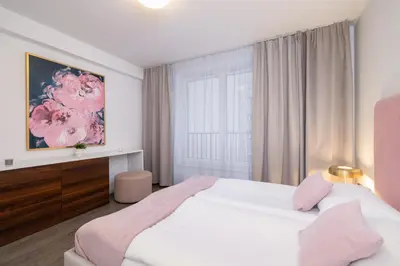 a white bedroom with a large bed and a window at Blue and Green Apartment with Bright Pink Bedroom in Kraków by Noclegi Renters in Kraków