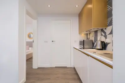 a kitchen with white cabinets and a counter top at Blue and Green Apartment with Bright Pink Bedroom in Kraków by Noclegi Renters in Kraków