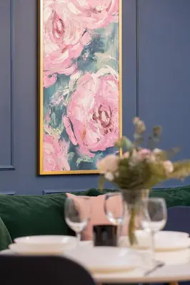 a vase of flowers on a table with a painting at Blue and Green Apartment with Bright Pink Bedroom in Kraków by Noclegi Renters in Kraków