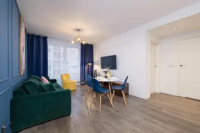 a living room with a green couch and a table at Blue and Green Apartment with Bright Pink Bedroom in Kraków by Noclegi Renters in Kraków