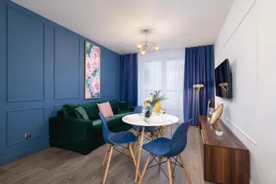 a living room with blue walls and a table and chairs at Blue and Green Apartment with Bright Pink Bedroom in Kraków by Noclegi Renters in Kraków