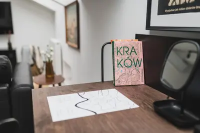 a book sitting on a table next to a tv at Vitrum Apartments in Kraków