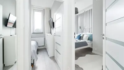 a small white room with a bed and a television at Bogusławskiego , Sun & Snow in Kraków