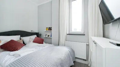 a white bedroom with a bed with red pillows at Bogusławskiego , Sun & Snow in Kraków