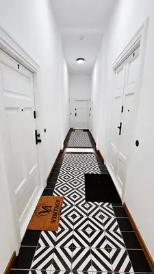 a hallway with white doors and a black and white tile floor at Deluxe Vintage Chic Apartment - Kazimierz Old Town in Kraków