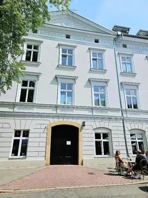 a white building with people sitting in chairs in front of it at Deluxe Vintage Chic Apartment - Kazimierz Old Town in Kraków