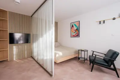 a bedroom with a bed and a chair and a television at Home From Home - Kraków, Podgórze in Kraków