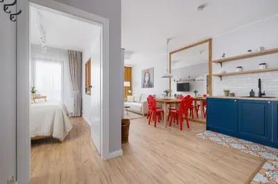 a kitchen and living room with a table and red chairs at Prandoty Beautiful Apartment with Balcony Cracow by Renters Prestige in Kraków