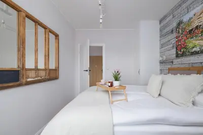 a bedroom with a white bed and a wooden table at Prandoty Beautiful Apartment with Balcony Cracow by Renters Prestige in Kraków