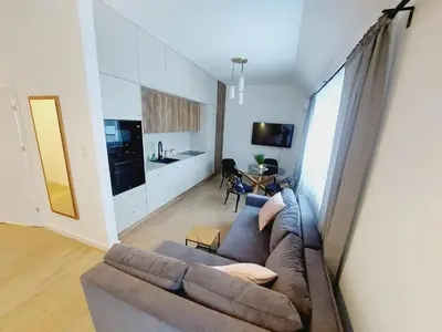 a living room with a couch and a kitchen at Komfortowe mieszkanie, duży taras, bezpłatny parking, AWG APARTMENTS in Kraków