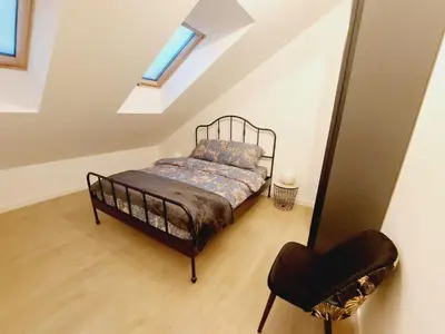 a bedroom with a bed and a chair in a attic at Komfortowe mieszkanie, duży taras, bezpłatny parking, AWG APARTMENTS in Kraków