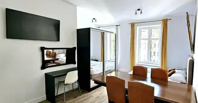 a dining room with a table and a bedroom at Pawia Apartments Centrum in Kraków