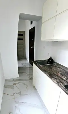a kitchen with white cabinets and a marble floor at Pawia Apartments Centrum in Kraków