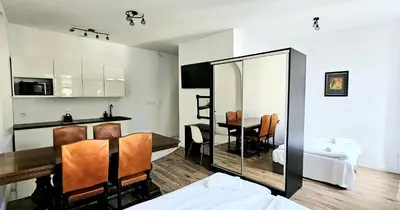 a living room with a dining room table and a mirror at Pawia Apartments Centrum in Kraków