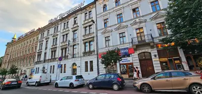 a large white building with cars parked in front of it at Pawia Apartments Centrum in Kraków