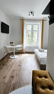 a room with a bed and a desk and a table at Pawia Apartments Centrum in Kraków