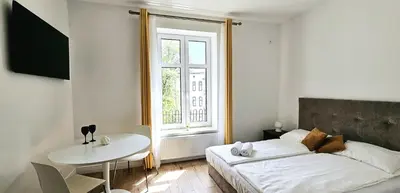 a bedroom with a bed and a table and a window at Pawia Apartments Centrum in Kraków
