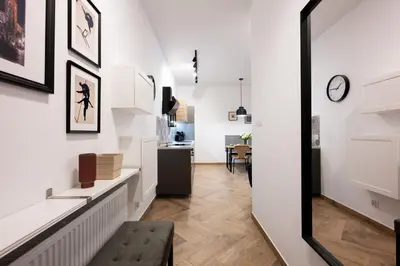 a living room with white walls and a hallway with a bench at Native Apartments Pułaskiego 6 in Kraków