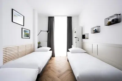 three beds in a room with white walls at Native Apartments Pułaskiego 6 in Kraków