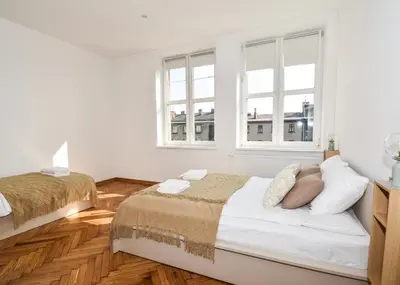 a bedroom with two beds and two windows at Sunny Corner in Kraków