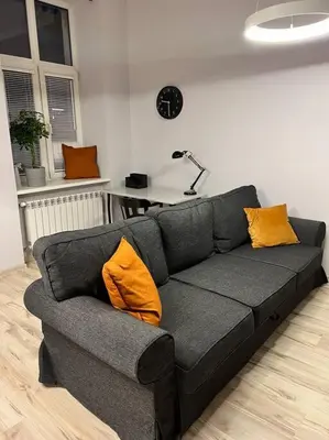 a couch with two orange pillows in a living room at V&O Apartament in the centre of Krakow in Kraków