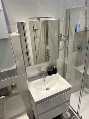 a white bathroom with a sink and a shower at V&O Apartament in the centre of Krakow in Kraków