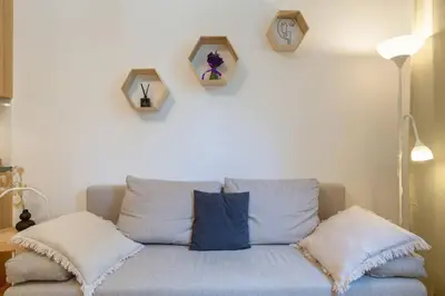 a blue couch with pillows and clocks on the wall at June B studio in Kraków