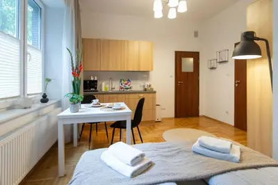a room with a bed and a table and a kitchen at May A studio in Kraków