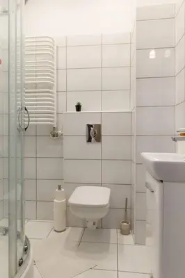 a white bathroom with a toilet and a sink at May A studio in Kraków