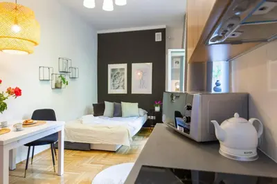 a small living room with a bed and a kitchen at May C studio w/balcony in Kraków