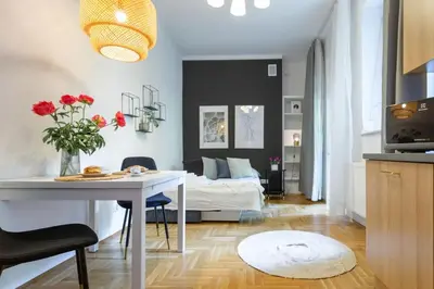 a living room with a table and a bed in a room at May C studio w/balcony in Kraków