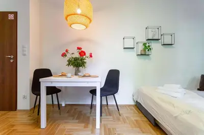 a white table with chairs and a vase of flowers at May C studio w/balcony in Kraków