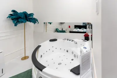 a white bathroom with a tub in a room at Apartament z Jacuzzi Kraków SHADOW Zamoyskiego in Kraków