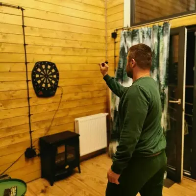 a man standing in a room with a dartboard on the wall at Dream Catcher House - dom do wynajęcia w górach in Limanowa