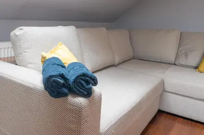 a blue blanket sitting on a white couch at A comfortable apartment midway Kraków-Oświęcim in Chrzanów