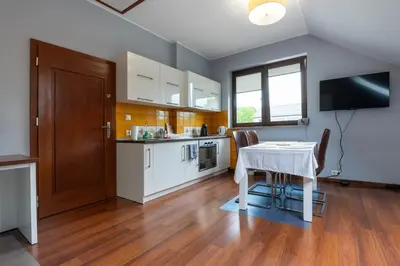 a kitchen with a table and a white table and chairs at A comfortable apartment midway Kraków-Oświęcim in Chrzanów