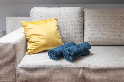 a pair of jeans sitting on a couch with a pillow at A comfortable apartment midway Kraków-Oświęcim in Chrzanów