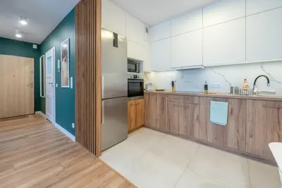 a kitchen with white cabinets and a refrigerator at Green Apartment Chrzanów in Chrzanów